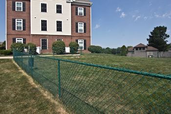 A green fence in front of a red brick building.